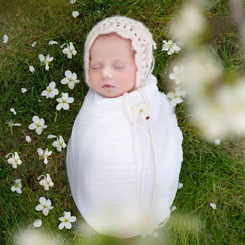 sleeping, swaddled baby wearing a bonnet